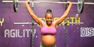 Jane Kabogo performs an overhead barbell press at the Kaizen gym.